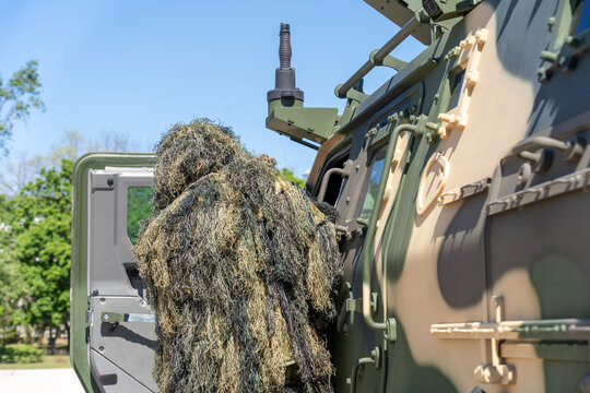 Camouflaged soldier beside a camouflaged modern 4x4 MRAP armored fighting vehicle