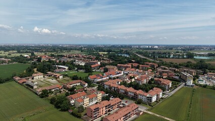 Aerial View of a European Town: A picturesque aerial perspective reveals a charming European town nestled amidst green fields, showcasing terracotta rooftops and a network of streets under a bright. © Andrew
