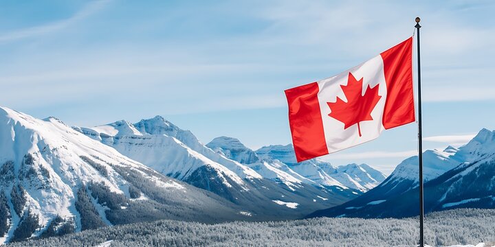 Canadian flag waving on a pole in snowy mountain landscape with blue sky