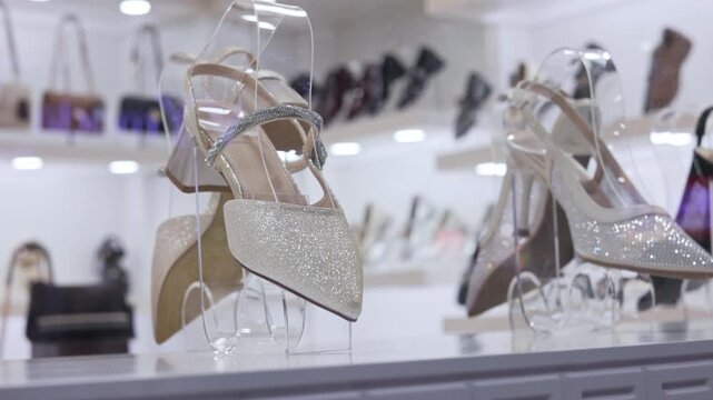 Glamorous and elegant women's high heeled shoes sparkling with glitter and rhinestones on a transparent display stand in a fashion boutique, showcasing the latest stylish footwear collection