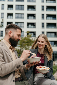 Business colleagues eating takeaway salad during outdoor lunch break