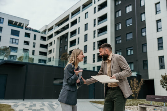 Business colleagues talking and exchanging documents outdoors
