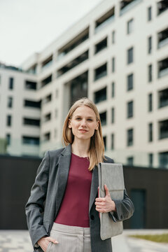 Young businesswoman standing confident holding folder document outside building