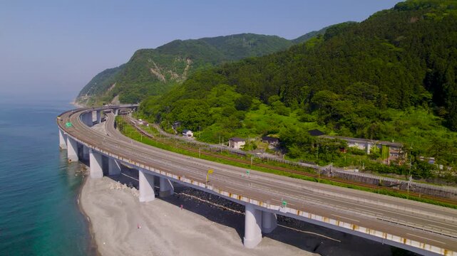 トンネルへと続く海岸線の高速道路 S字カーブの広がりを捉える前進空撮