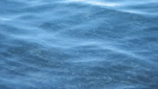 Serene close-up of blue water with gentle waves and slight ripples on the surface