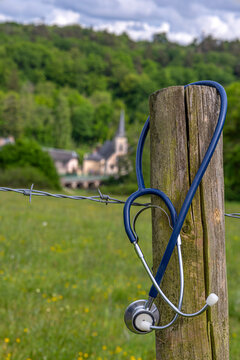 Stethoscope Hangs on Fence Near Village in Nature The concept of a medical desert, a shortage of rural doctors
