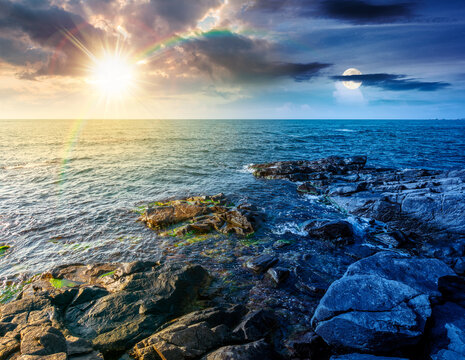 day meet night. sea coast with stones and boulders. view of beach with rock in seaweed. sun and moon on epic sky above horizon. autumn equinox harmony concept for astrology background