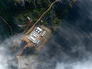 Fototapeta premium Aerial view of mountain photovoltaic solar power station surrounded by clouds and mist