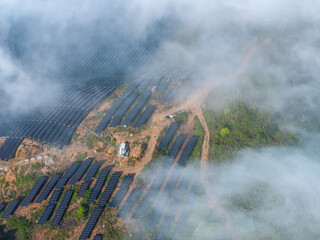 Fototapeta premium aerial view of a mountain photovoltaic power station shrouded in clouds and mist