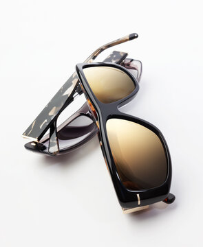 Close up of elegant black and tortoiseshell sunglasses folded on white background