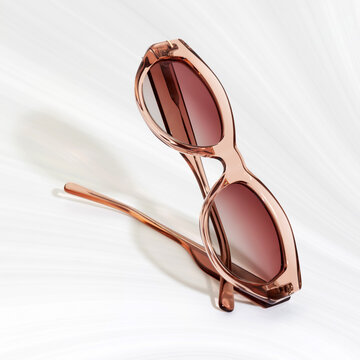 Close up of elegant translucent rose gold sunglasses on white textured background