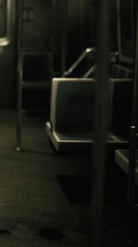 A bus with empty seats and metallic poles is seen at night. The bus is dimly lit and shows the quiet environment inside with no people present.