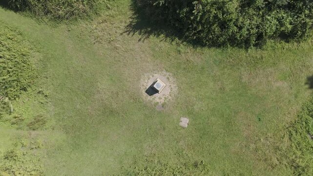 4K aerial drone view descending over hilltop trig point earthworks.