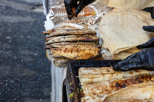 Traditional Turkish street food balik ekmek wrap being prepared with grilled mackerel fish and lavash bread near Galata Bridge in Istanbul