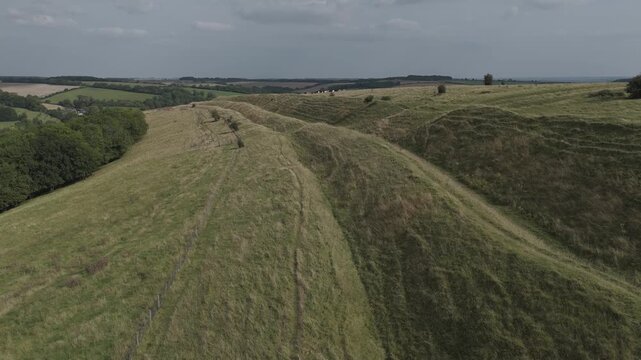4K drone flight over steep green hill fort earthworks and ramparts.