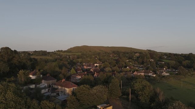 4K aerial shot of village and Hambledon Hill in golden hour light.