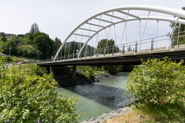 Fototapeta premium Modern White Arch Pedestrian Bridge Over River at Vedder Park in Chilliwack, BC, Canada