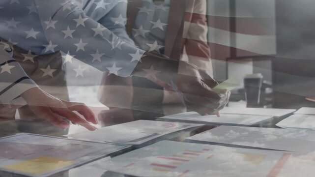 Business team leaning and pointing, stacking charts for filing with flag overlay drifting over docs