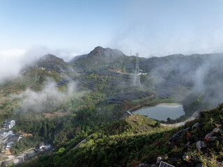Fototapeta premium Scenic view of misty mountain terraces with a reservoir and power transmission towers