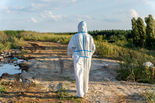 An ecologist walks through a garbage dump wearing a white suit to study the environment and waste management in the area