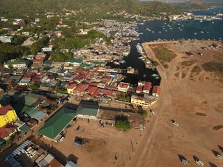Aerial drone view of the floating fishing village in Coron, Palawan, Philippines. Traditional stilt houses, colorful rooftops, and Filipino outrigger boats line the coastal waters © akturer