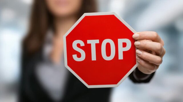 Businesswoman holding stop sign, concept for warning, danger, and restriction message