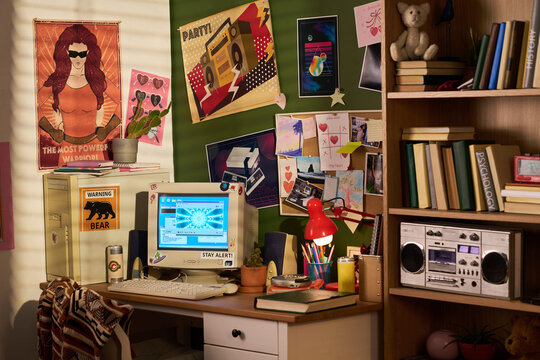 Wide shot of retro home office setup featuring vintage computer, books, posters, and stereo, evoking nostalgic digital culture. Ideal for technology history, youth lifestyle