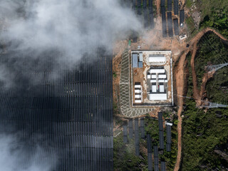 Fototapeta premium aerial view of mountain top solar power station and substation surrounded by clouds