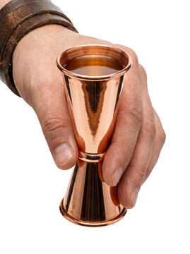 Hand holding a copper cocktail jigger with liquid, transparent background