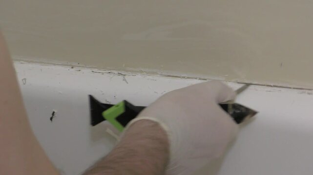 plumer man cleans gaps in tile removes mold in washroom bathroom