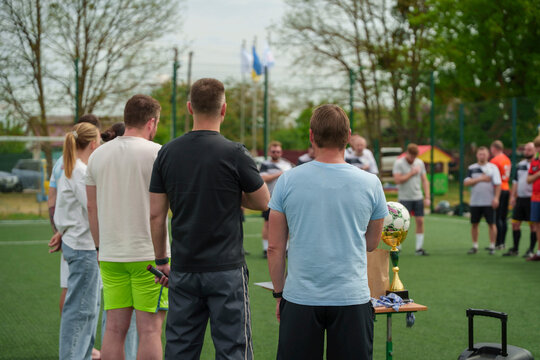 Soccer team gathered on the field with a trophy table in front of them outdoors, championship celebration moment, sports success concept.