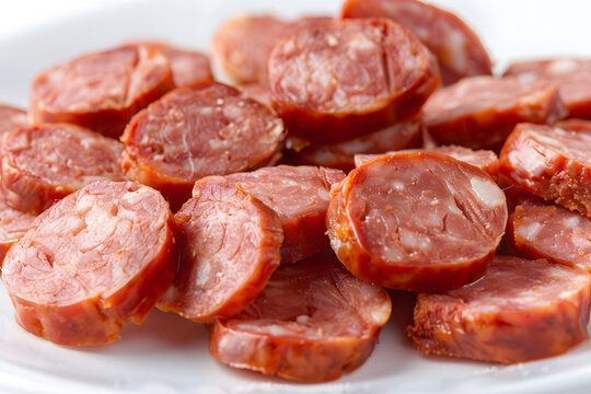 Smoked Polish kielbasa sausage with sliced pieces on white background, traditional meat product with detailed texture.