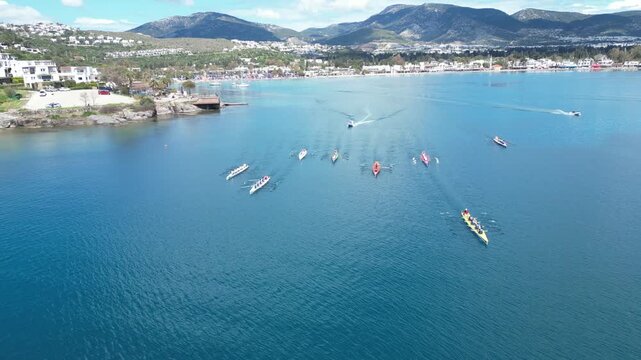 Aerial View of Professional Rowing Teams Competing in a Regatta near Scenic Coastal Town with Mountains. High quality 4k footage