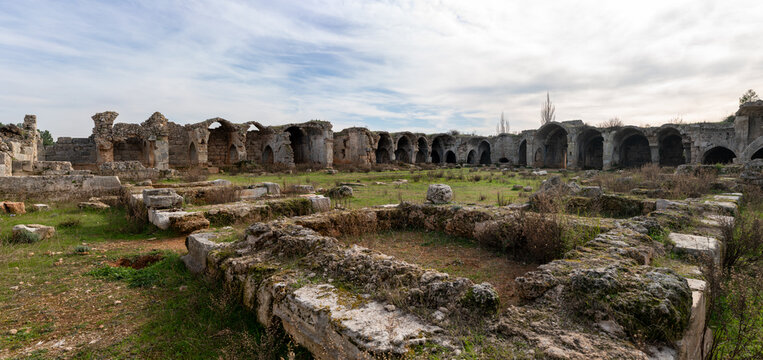 Ruins of a historic Seljuk caravanserai standing within the Mediterranean countryside of Antalya, T&uuml;rkiye, reflecting the architectural heritage of ancient Anatolian trade routes.
