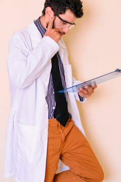 Bearded doctor analyzing exams in the office. Doctor's outfit with a white lab coat and striped shirt. Scientist, sports doctor, gynecologist, urologist, psychiatrist.