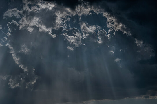 The natural phenomenon of sunlight shining through clouds, often referred to as "God rays" or the Tyndall effect. As a wallpaper, background