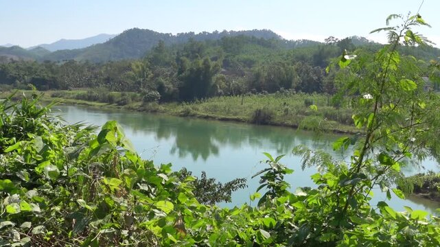 A mountain river with standing water at the outlet of the plain. Secondary rain forests and shores are occupied by plantations. Thailand.