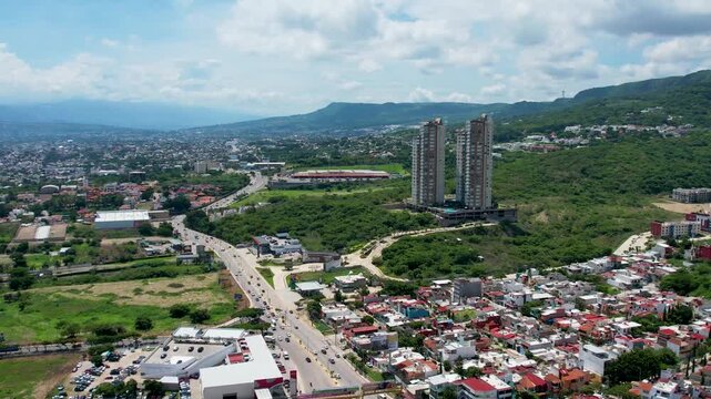 Aerial drone view of modern skyscraper towers and cityscape highway on a sunny day.