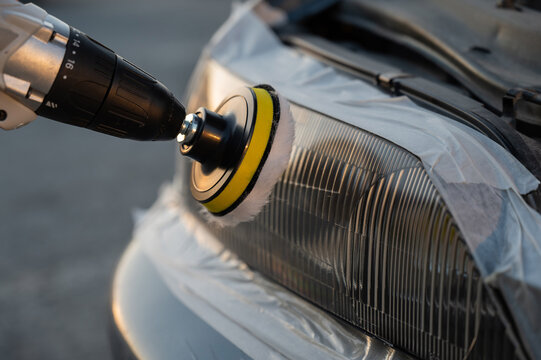 The process of polishing car headlights outdoors. 