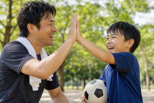サッカーの後にハイタッチする父と息子