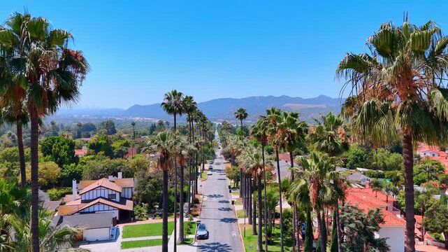 Footage over the road crossing the beautiful residential area with lovely red-roofed houses. Approaching the Hollywood Hills in Los Angeles, California, USA.