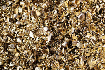 Golden metal shavings texture background. Industrial machining waste from CNC turning and milling process. Metallic scrap curls and brass swarf closeup for engineering industry concept