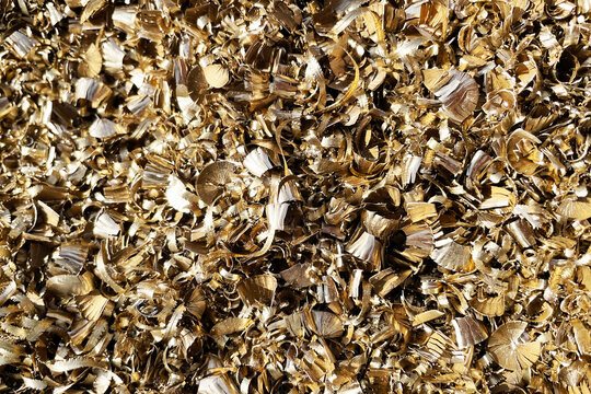 Golden metal shavings texture background. Industrial machining waste from CNC turning and milling process. Metallic scrap curls and brass swarf closeup for engineering industry concept