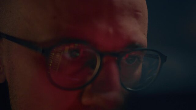 Close up: man crypto trader wearing glasses closely analyzes cryptocurrency or stock market data with candlestick charts and financial graphs, reflecting in lenses, monitoring trends. Eyeglasses