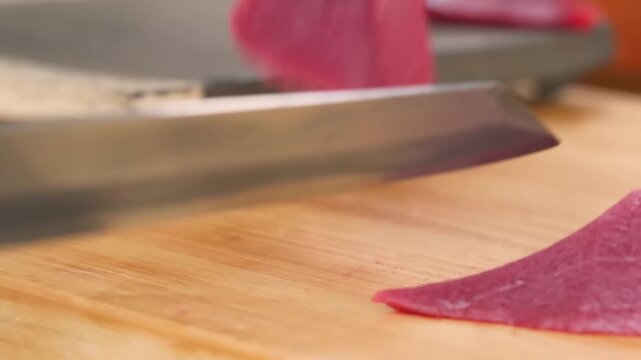 close-up shot of a professional sushi chef using a sharp Japanese sashimi knife to precisely slice through a high-quality, lean bluefin tuna akami saku block.