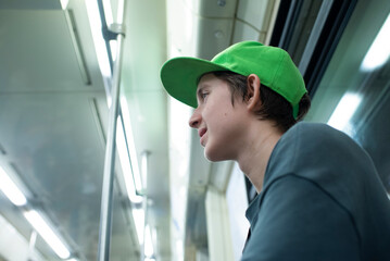  Profile portrait of teenage boy in bright green cap riding inside subway car © Ruslan Russland