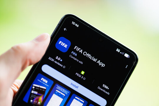 Close-up of a hand holding a smartphone displaying the FIFA Official App on the Google Play Store