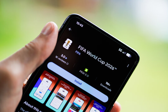 Close-up of a hand holding a smartphone displaying the FIFA World Cup 2026 app on the Google Play Store