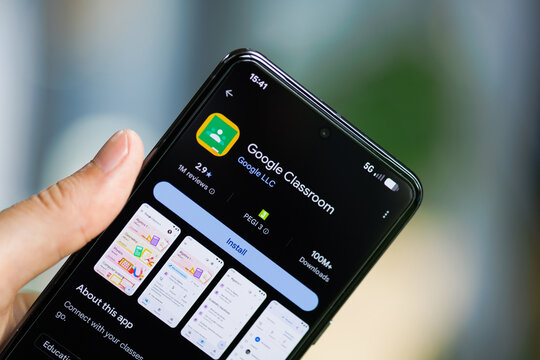 Close-up of a hand holding a smartphone displaying the Google Classroom app on the Google Play Store