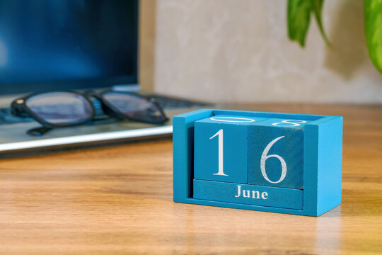 Desktop calendar made of wooden blocks displaying June 16 on table